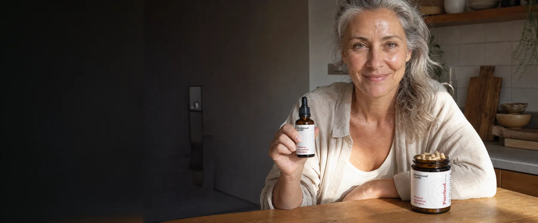 A woman taking Blushwood Berry Extract tincture as part of her morning routine, with the capsules on the counter